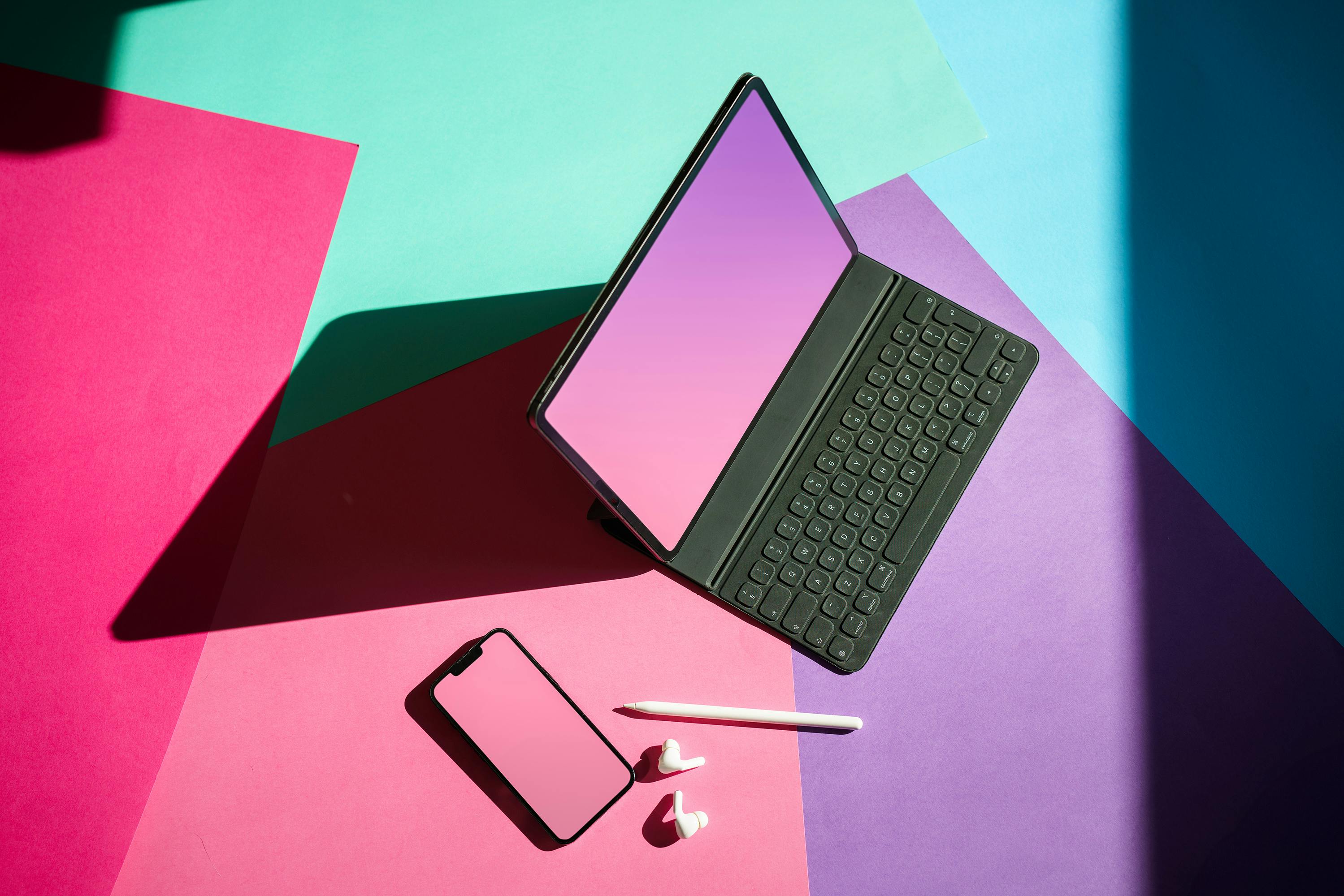 Image of a laptp, phone , earpods and a pen