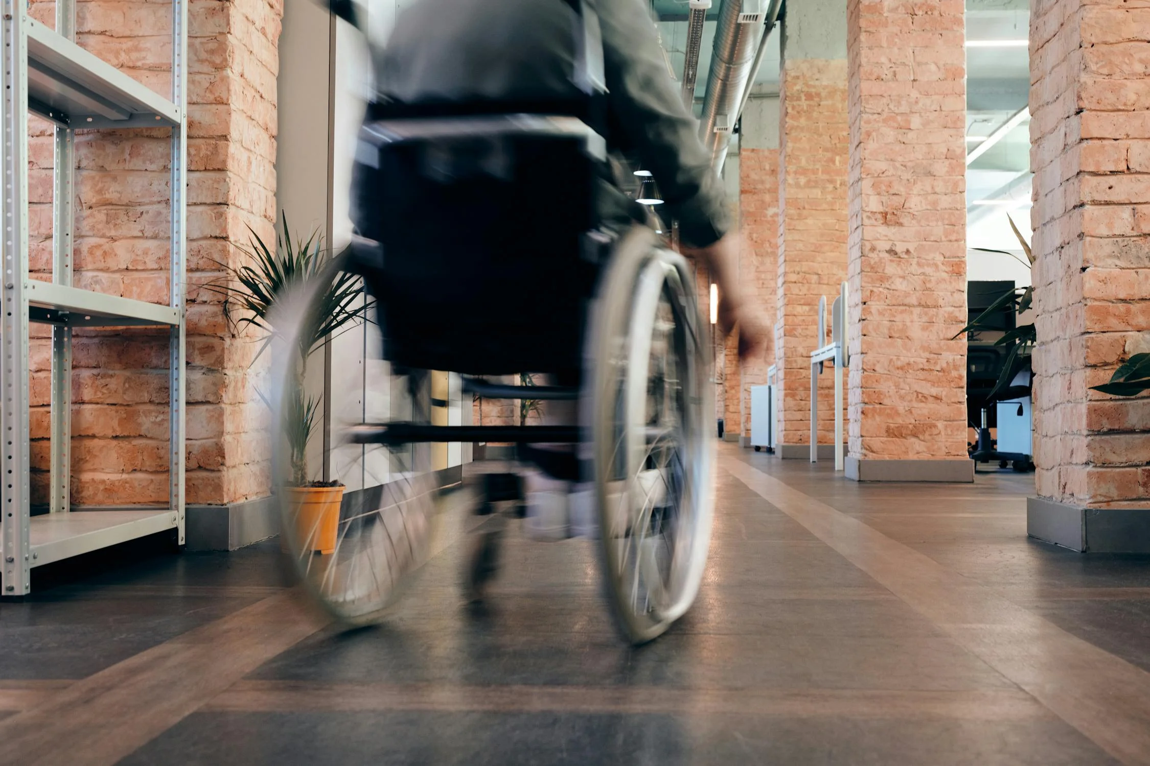 A person in a wheelchair moving through a modern workspace, symbolizing inclusive design and accessibility.