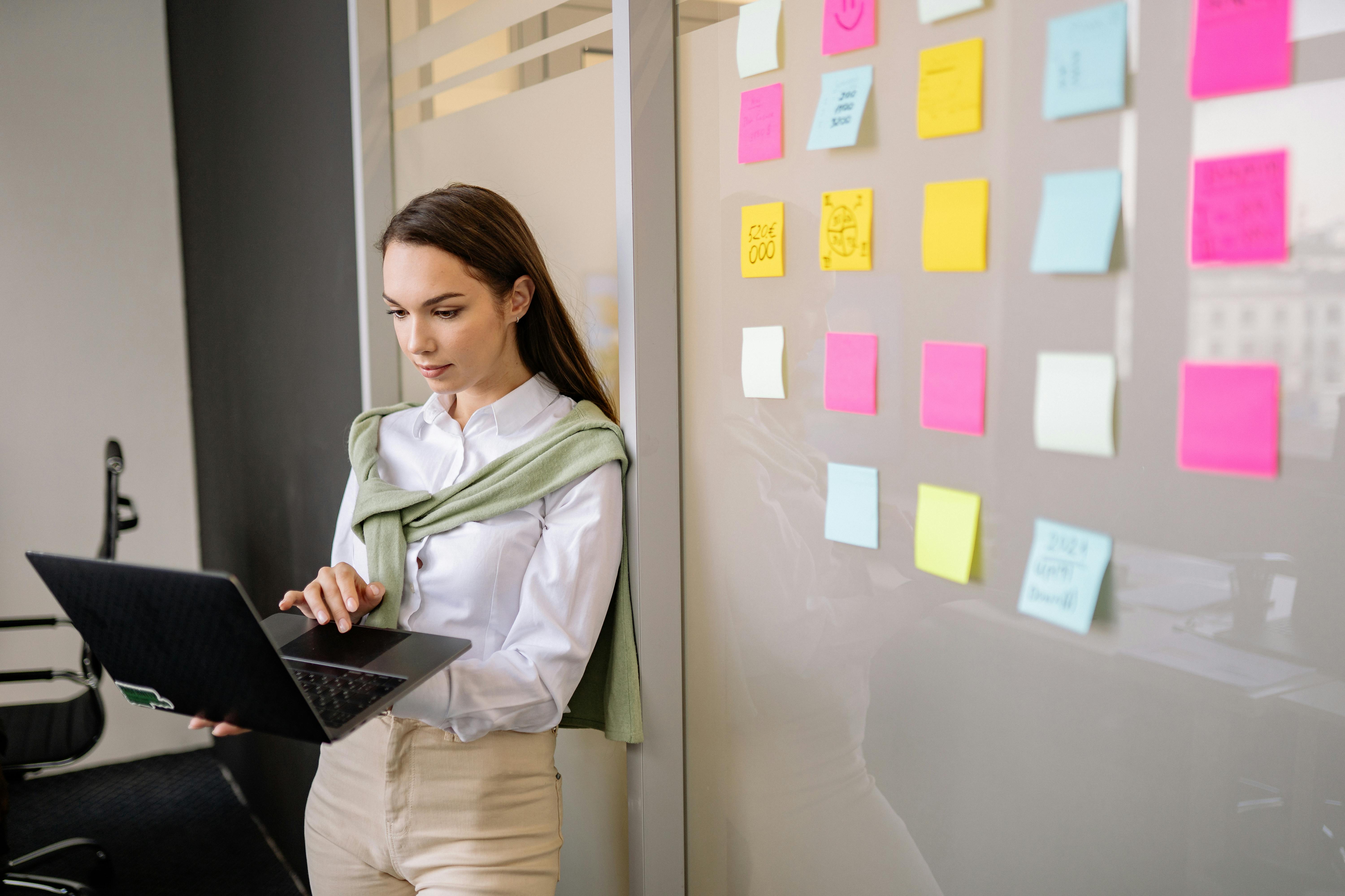 A woman standing next to the wall with sticky notes